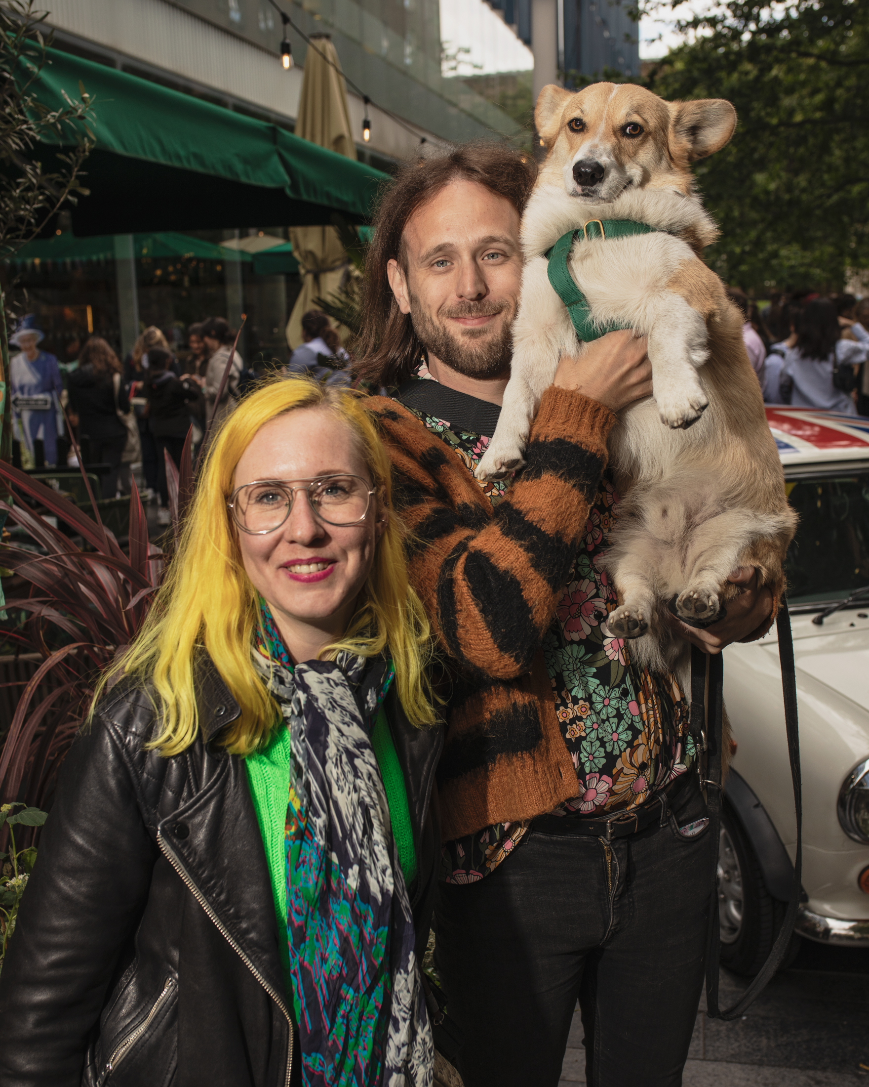 A couple holding up a corgi at the London corgi cafe for Platinum Jubilee