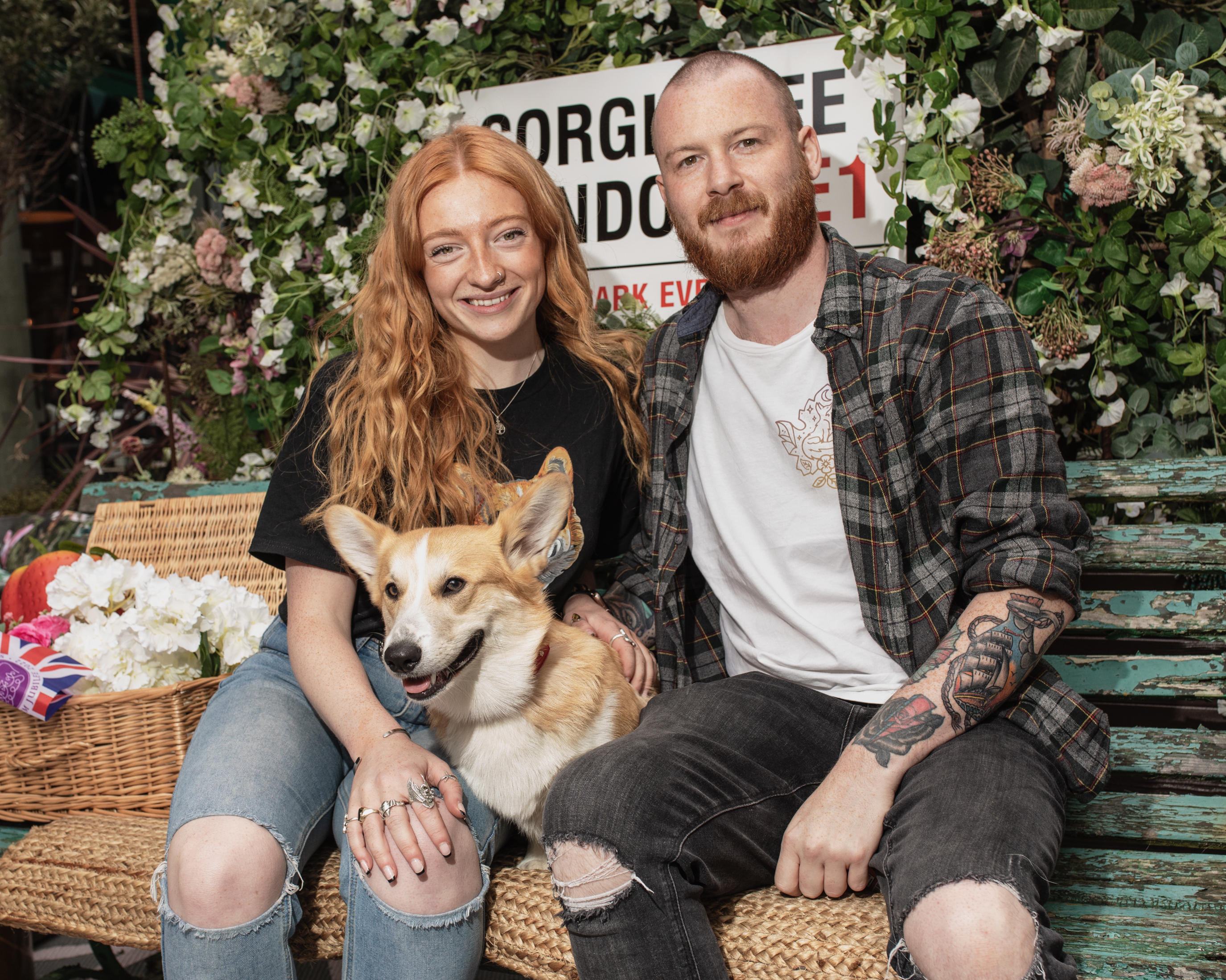 A couple sitting on a bench with their corgi at the London corgi cafe for Platinum Jubilee