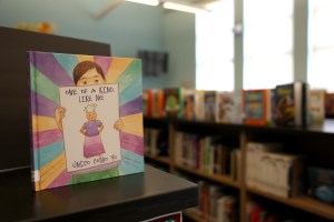 A children's book titled "One of a  Just Like Me" sits atop a shelf in school library