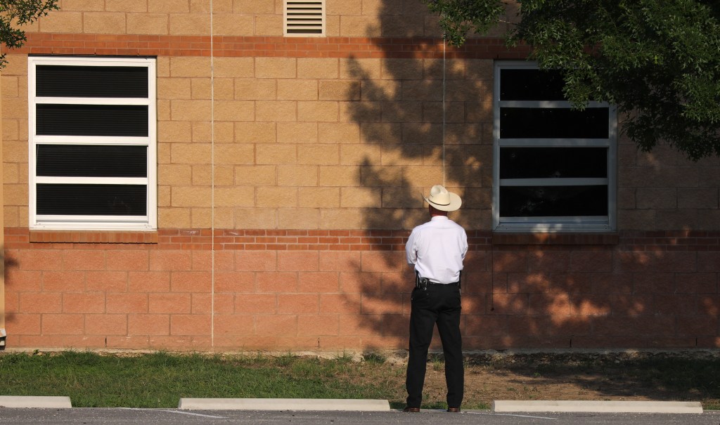 An officer stands in front of a broken window of Robb Elementary School, the site of the May 24th mass shooting on May 30, 2022 in Uvalde, Texas.