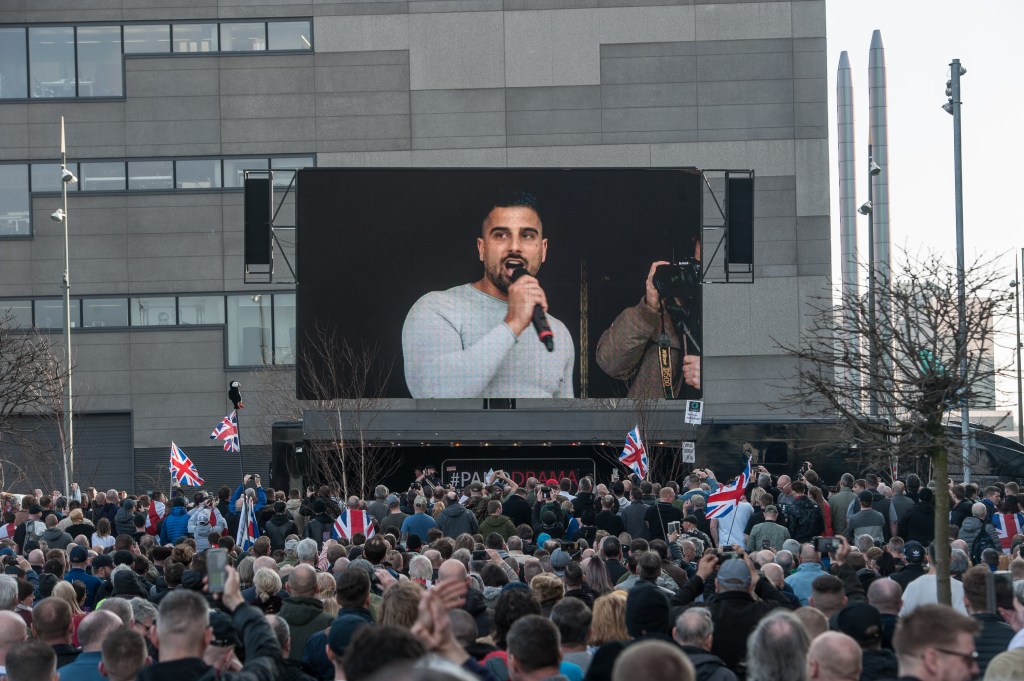 People in crowd looking at photo of avi yemini