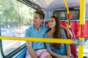 Portrait of a happy young straight couple riding the bus in London and smiling