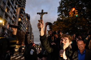 Nicholas Fuentes holds up a cross while speaking to people associated with the far-right group America First attend an anti-vaccine protest in front of Gracie Mansion on November 13, 2021 in New York City.