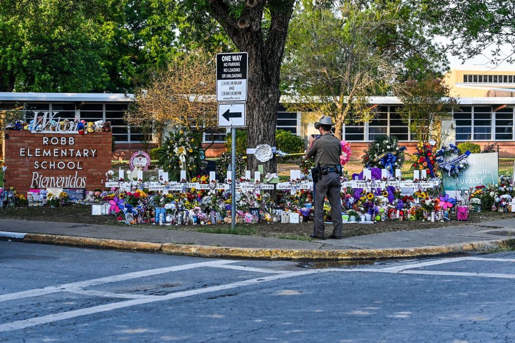 A police officer stands near the makeshift memorial for the shooting victims outside Robb Elementary School in Uvalde, Texas, on May 28, 2022.