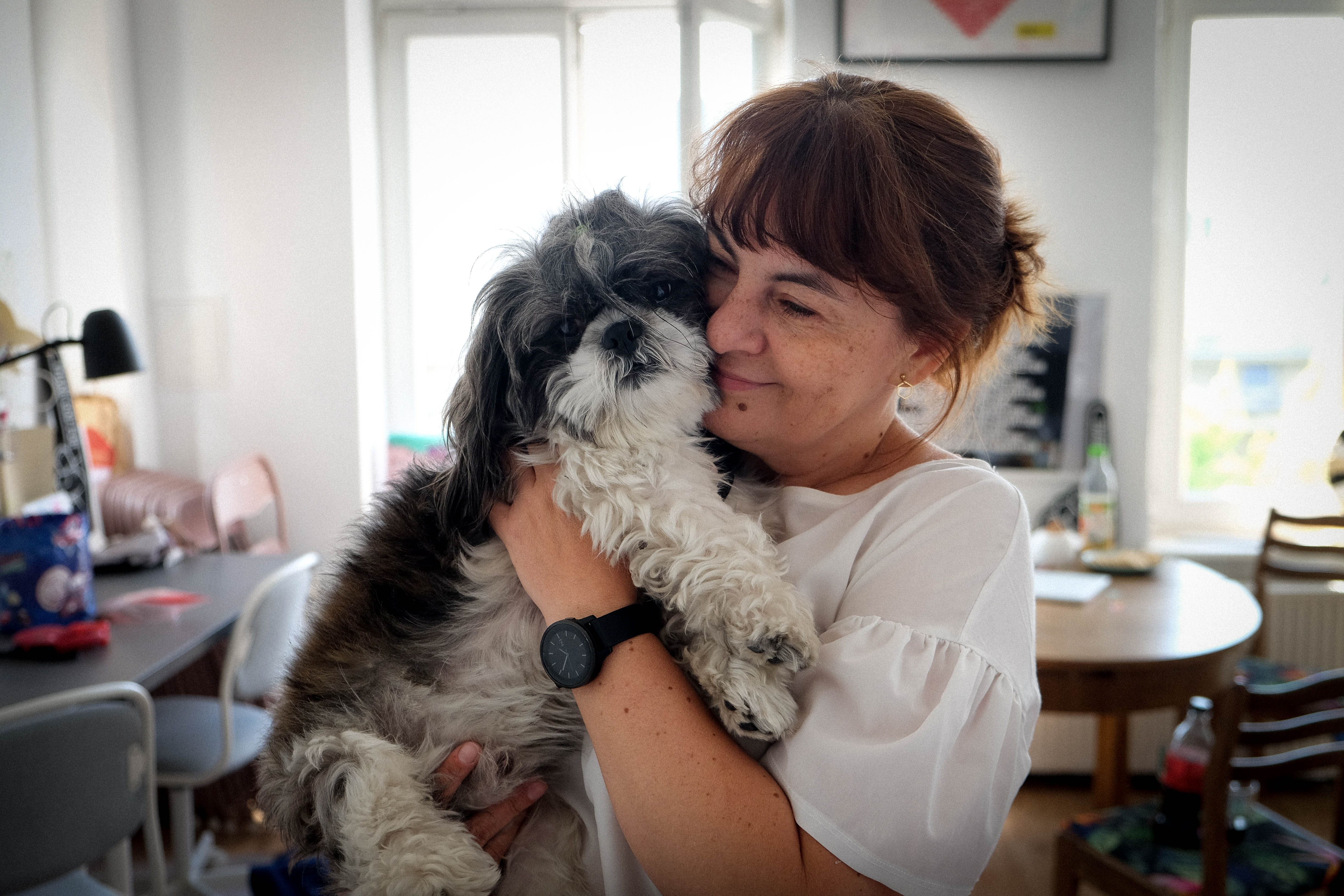 Eine Frau kuschelt lächelnd mit einem Hund