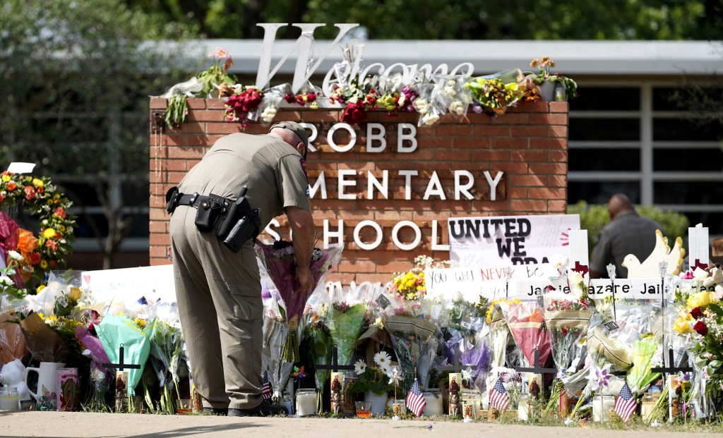 A police officer lays flowers outside Robb Elementary School in the town of Uvalde, Texas, the United States, May 27, 2022.