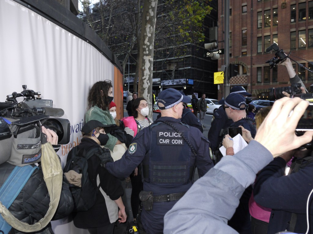 Climate activists undergo police search while protesting for deeper emissions cuts