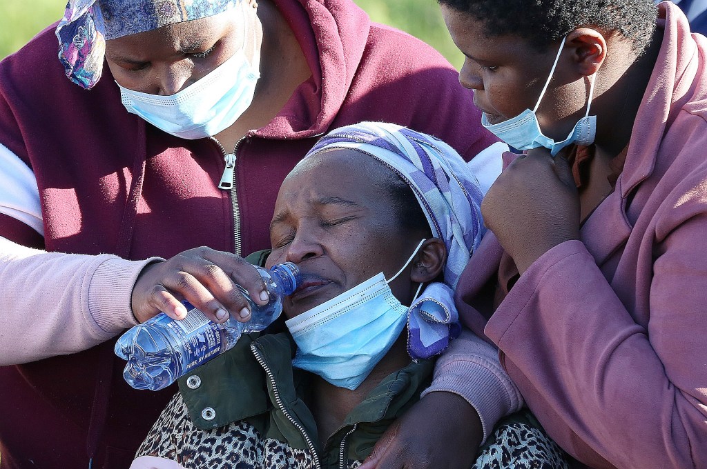 People comfort a family member of dead teenager outside a mortuary in East London, South Africa.