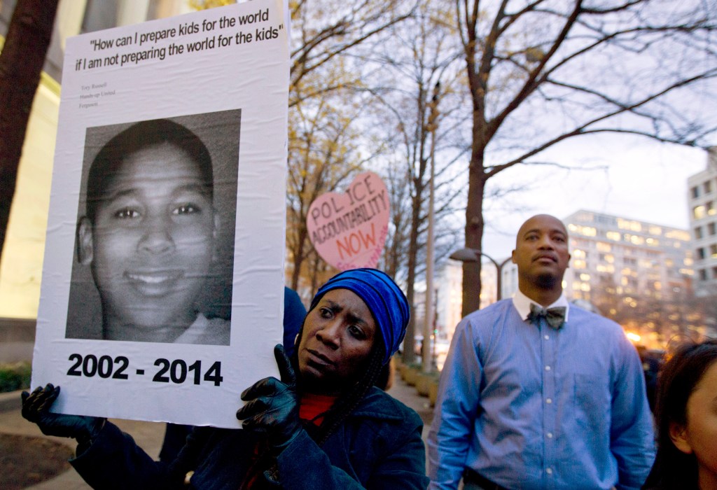 In this Dec. 1, 2014 file photo, Tomiko Shine holds up a poster of Tamir Rice during a protest in Washington.