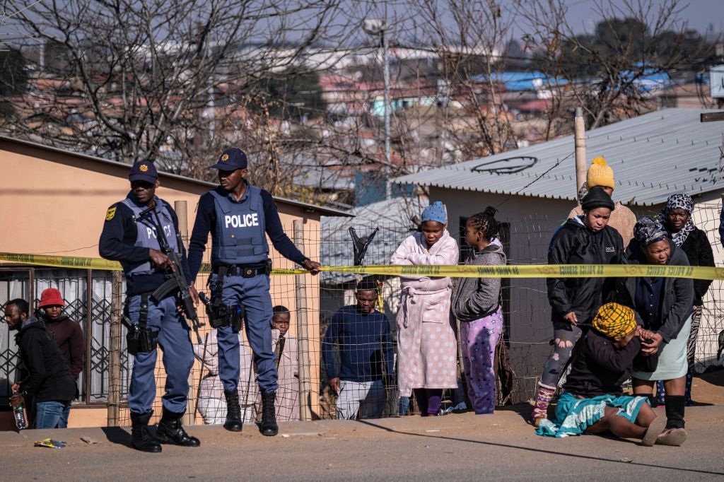 A relative of one of the victims shot dead in a tavern in Soweto reacts next to the crime scene in Soweto.