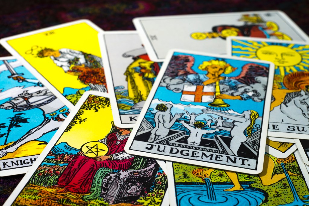 An array of tarot cards is shown strewn on a table, with the Judgment card from the Major Arcana facing upwards on top.