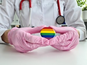 A doctor holding an LGTQ Pride pin.