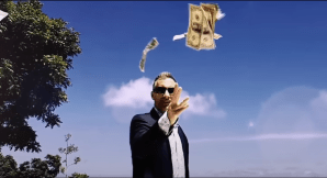 A screenshot from HBO's 'The Anarchists' showing a man in a suit and sunglasses throwing cash into the air