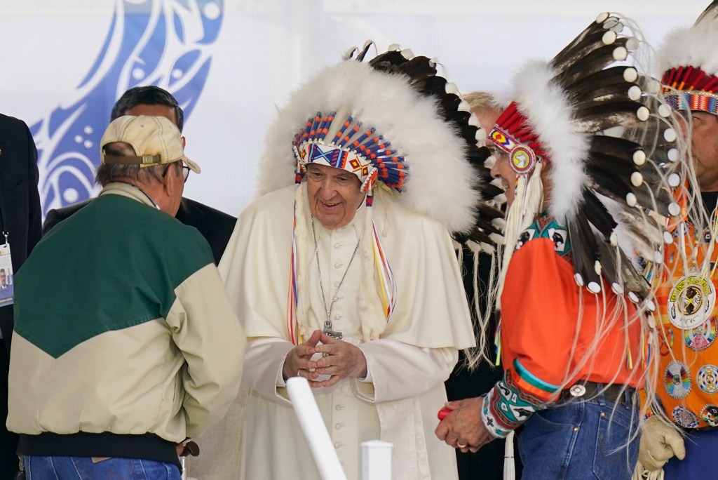 Pope Francis dons a headdress during a visit with Indigenous peoples at Maskwaci, the former Ermineskin Residential School, Monday, July 25, 2022, in Maskwacis, Alberta