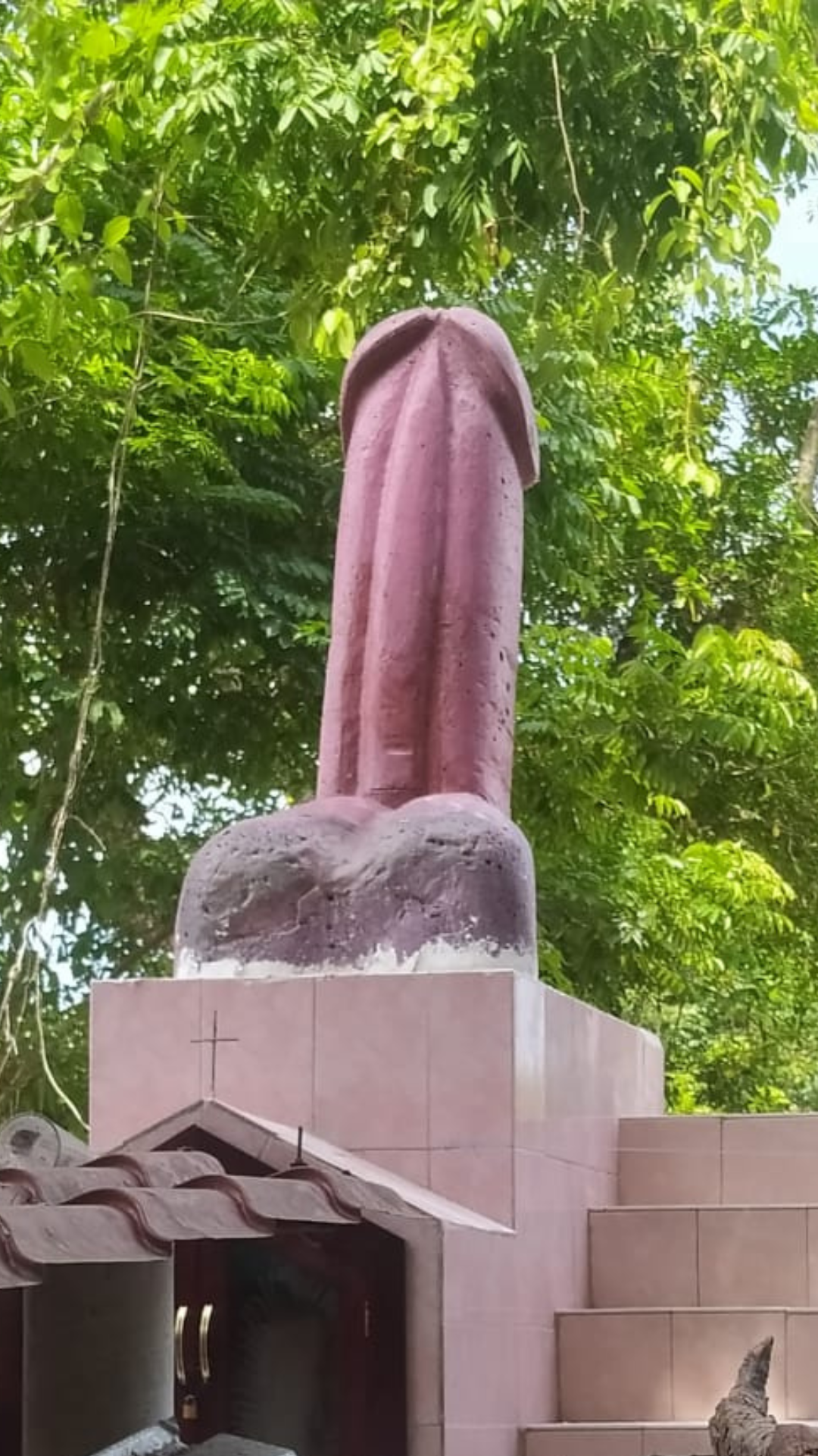 Eine große Penisstatue auf einer Gruft mit rosa Fliesen