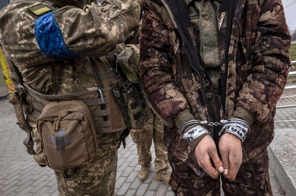 Prajurit Ukraina berdiri di sebelah tentara Rusia yang tangannya diborgol di Kharkiv pada 31 Maret 2022. (Foto oleh Fadel Senna/AFP via Getty Images)