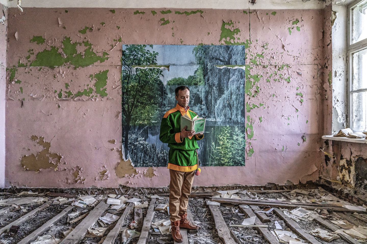 A man reading a book in a dilapidated building.