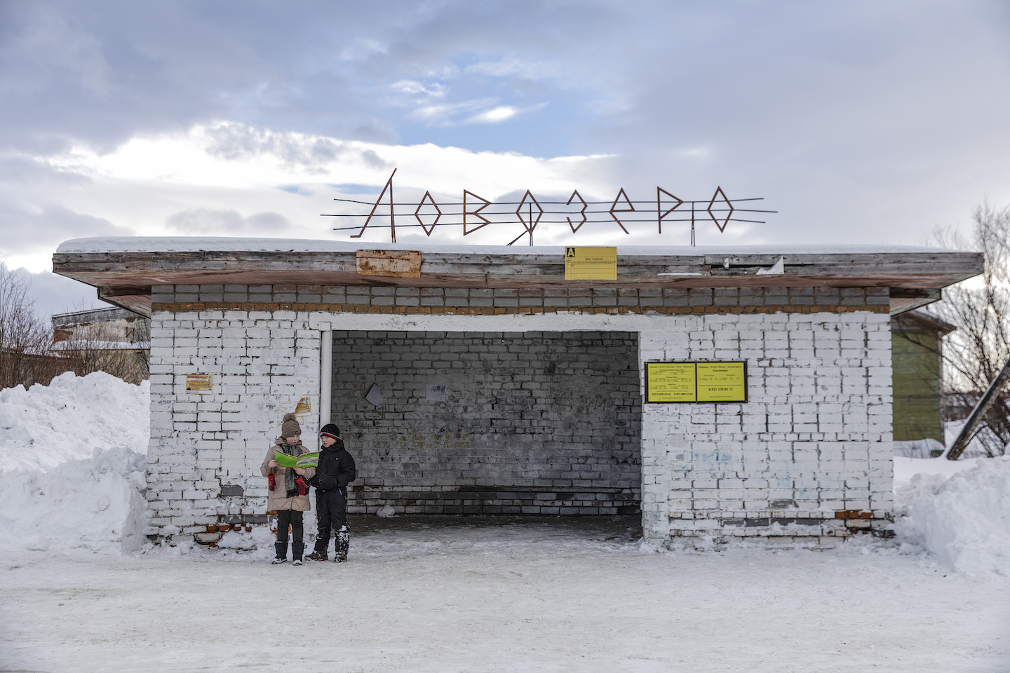 Two children waiting for a bus.