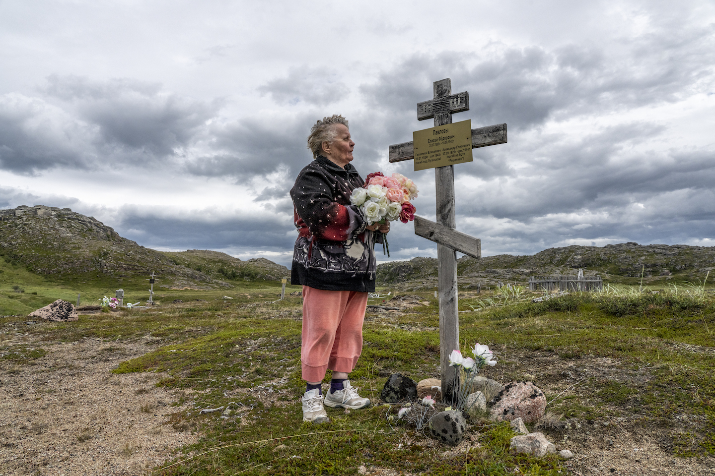 A woman lays flowers at a grave site.