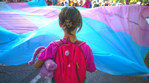 A girl holds the Transgender Pride flag