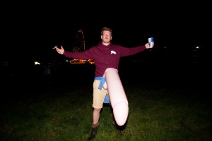 A man in a rude costume holding a drink and a cigarette