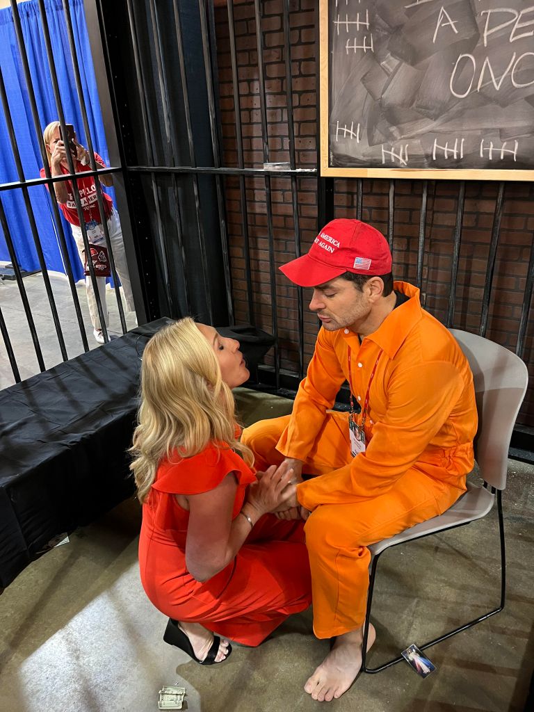 Marjorie Taylor Greene and J6 defendant Brandon Straka​ pray together inside a cage at CPAC.