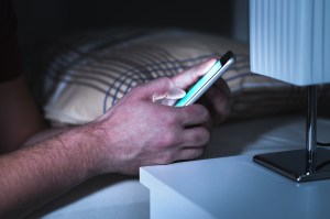 Someone using a phone in bed. Getty Images