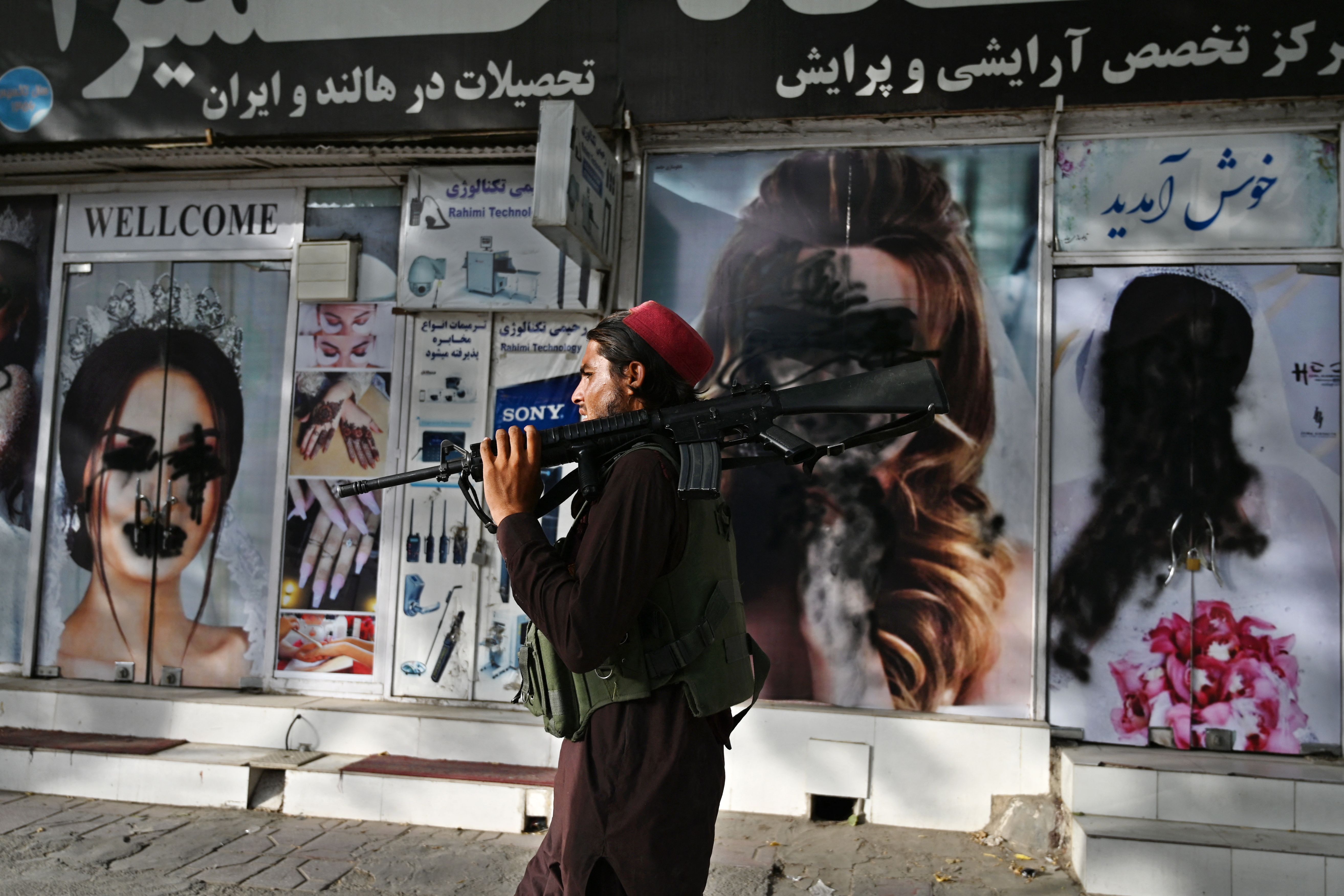 A Taliban fighter walks past a beauty salon with images of women defaced using spray paint in Shar-e-Naw in Kabul on August 18, 2021. Photo: Wakil Kohsar /AFP via Getty Images