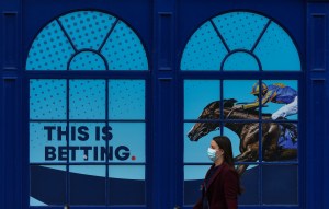 A woman walks past a sign advertising a betting website.