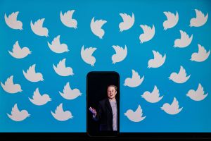 This illustration photo taken on August 5, 2022 shows a cellphone displaying a photo of Elon Musk placed on a computer monitor filled with Twitter logos in Washington, DC.