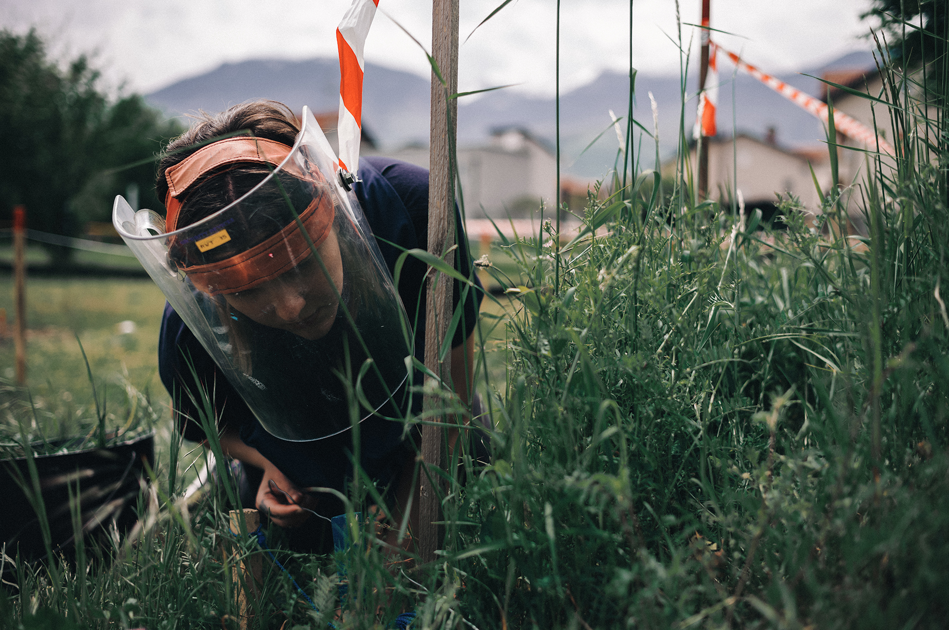 Dasha Starikova uses a metal strand to check for tripwires hidden in the tall grass at the MAT Kosovo training center in Peja.