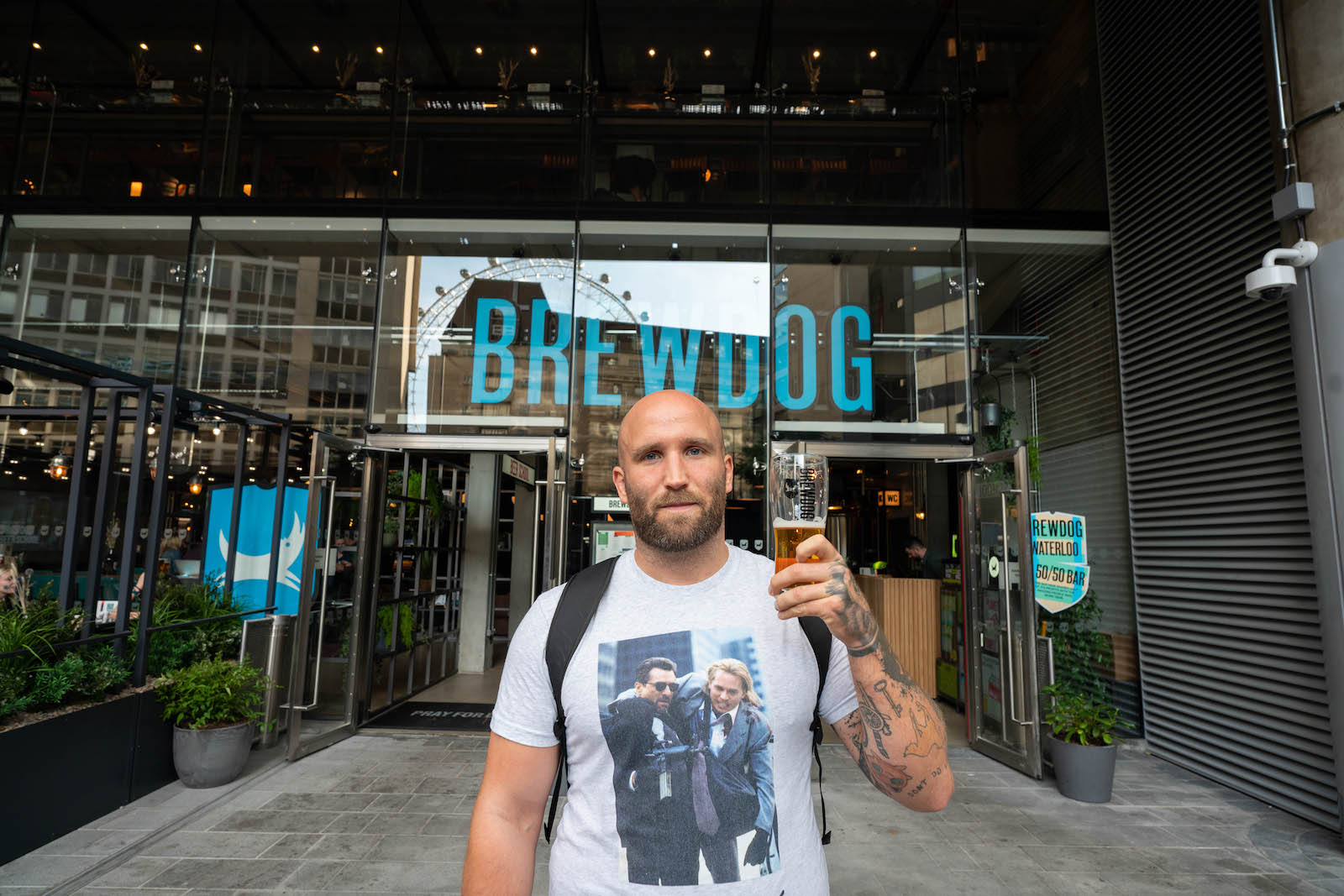 Writer Tom Usher holding a pint of beer outside the giant Brewdog