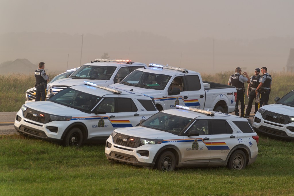 Police and investigators are seen at the side of the road outside Rosthern, Sask., on Wednesday, Sept. 7, 2022.