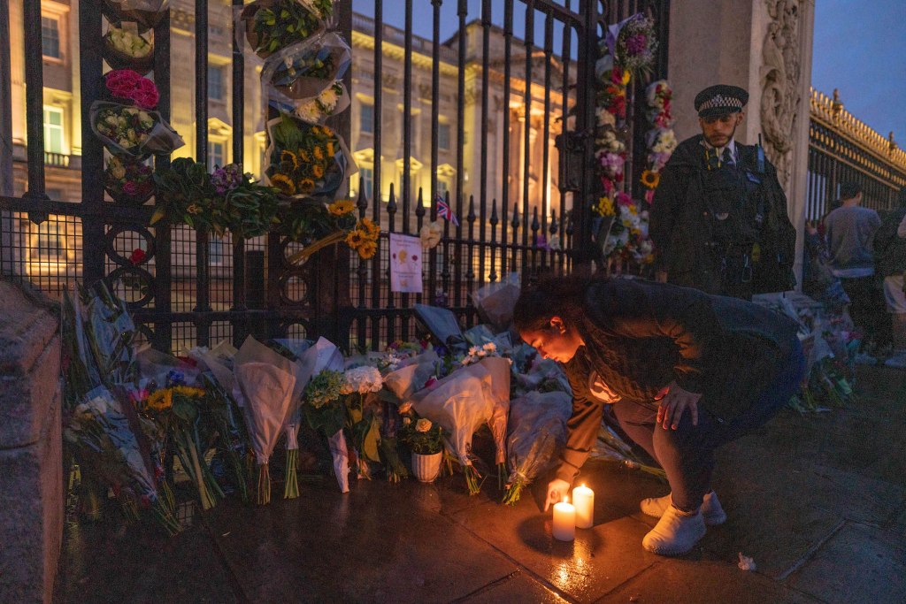 A woman lays candles outside Buckingham Palace on day the Queen died