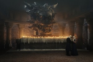 Two characters from House of the Dragon standing in front of a dragon's s