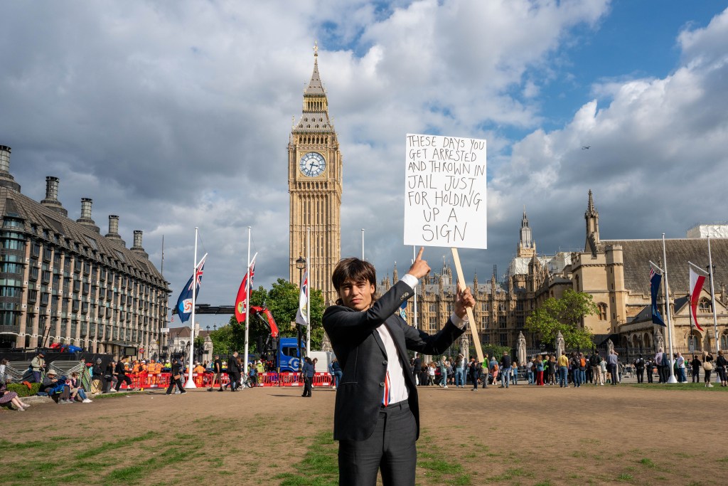 Author holding up sign reading "These days you get arrested and thrown in jail for just holding up a sign"