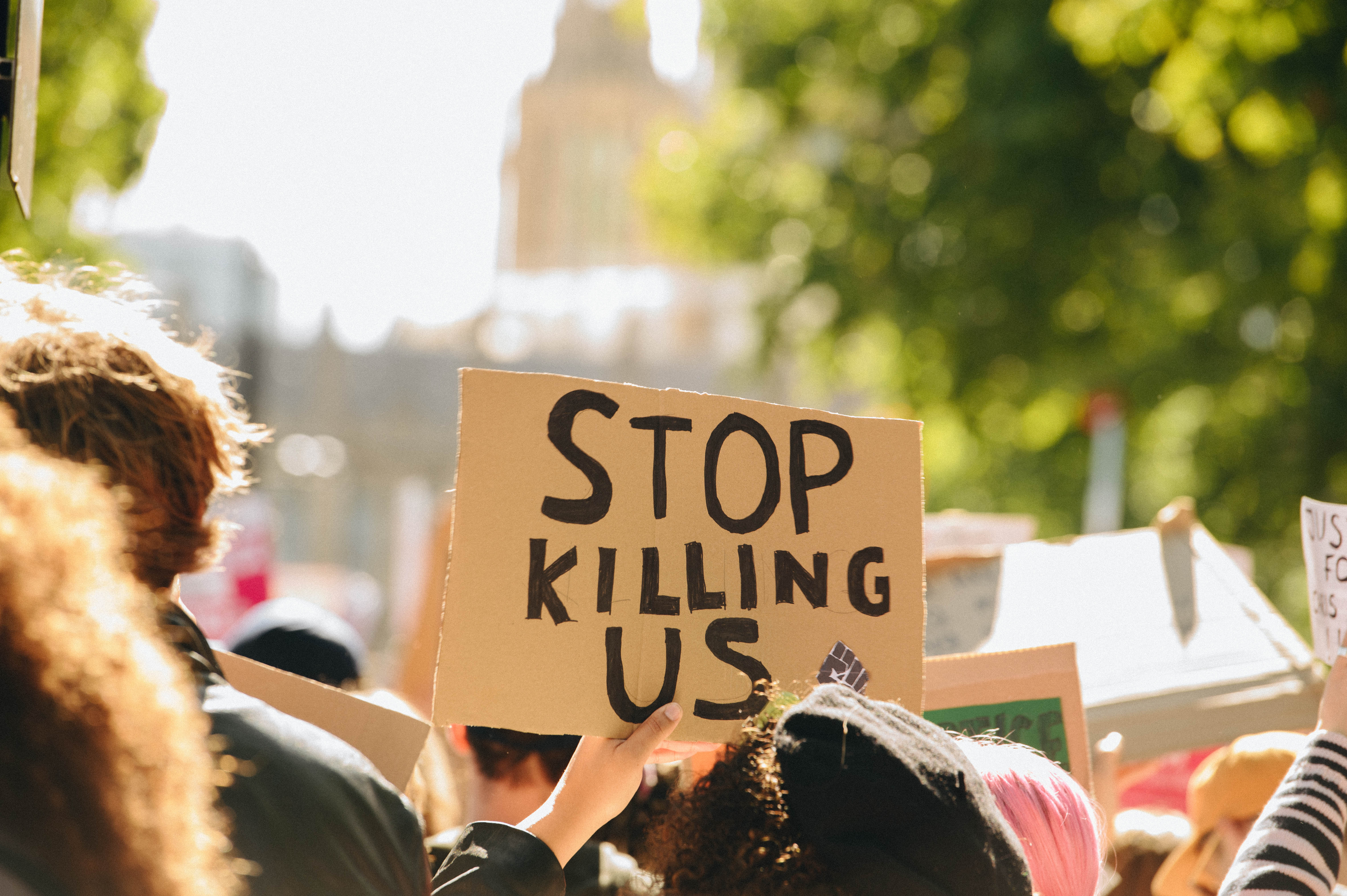 A person holds up a sign saying Stop Killing Us at the Chris Kaba protest