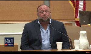 Alex Jones sits in front of a microphone in court; his eyes appear closed.