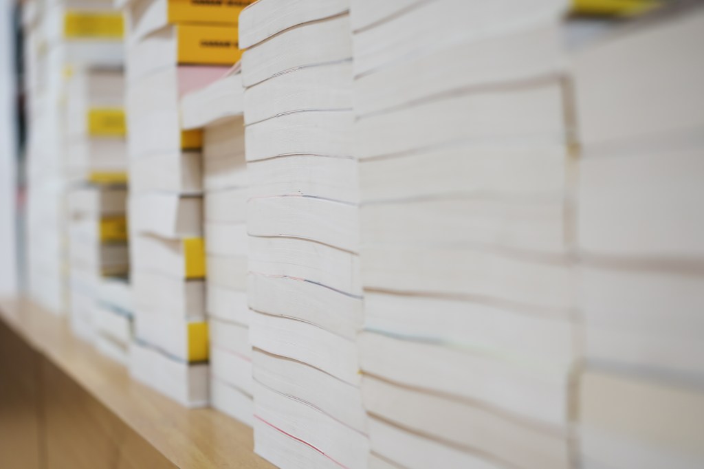 A stack of thick textbooks on a shelf