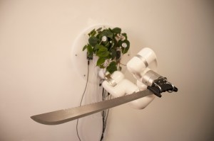 A houseplant connected to wires and a robotic arm holding a long knife