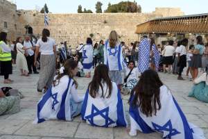 Women demonstrators draped with Israeli flags sit near the Western Wall in the old city of Jerusalem on May 29, 2022