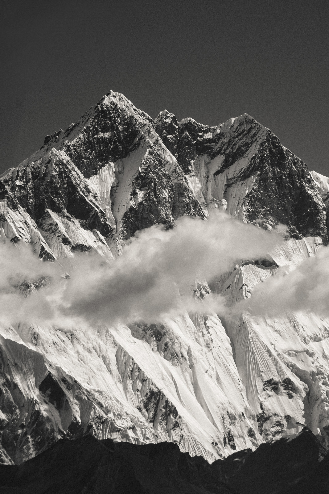 namche bazar to tengboche – black and white photo of a wide mountain peak covered in a thick layer of snow and surrounded by thin clouds.