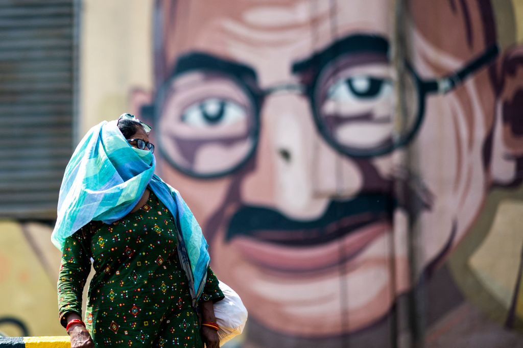 woman walks past a mural with gandhi