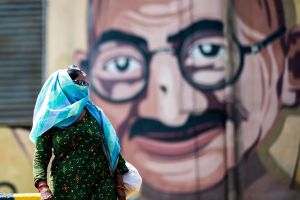 woman walks past a mural with gandhi