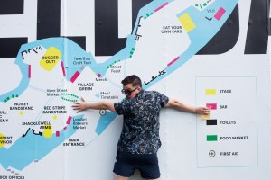 Man holding a pint in front of a music festival map