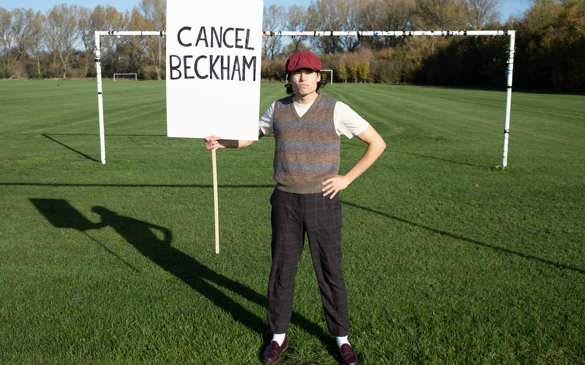 Man dressed as woke lad carrying Cancel Beckham sign