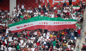 Pendukung kesebelasan Iran membentangkan bendera negara yang bertuliskan “Women, Life, Freedom” memprotes negaranya pada Piala Dunia Qatar 2022.