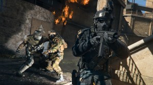 A screenshot of Call of Duty: Warzone 2 depicting a soldier stabbing another soldier in the background, while a man in black tactical gear walks into the foreground pointing a weapon.