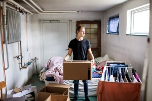 thoughtful man carrying cardboard box while sanding in bedroom