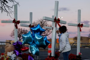 A Walmart employee signs a note on a wooden cross near the site of a shooting at the store on November 28, 2022 in Chesapeake, Virginia.